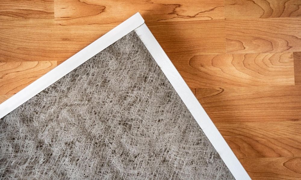 An air filter laid out carefully on a wooden floor.